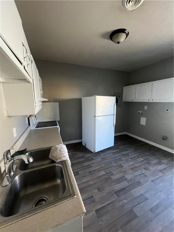 4432 E 10th St, Kansas City, MO 64127 - kitchen featuring freestanding refrigerator, dark wood-type flooring, range, white cabinetry, and light countertops
