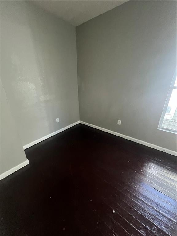 4432 E 10th St, Kansas City, MO 64127 - spare room featuring baseboards and hardwood / wood-style flooring