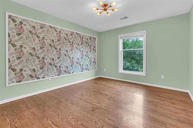 14440 W 187th Ter, Olathe, KS 66062 - empty room featuring wood finished floors, a chandelier, and a textured ceiling