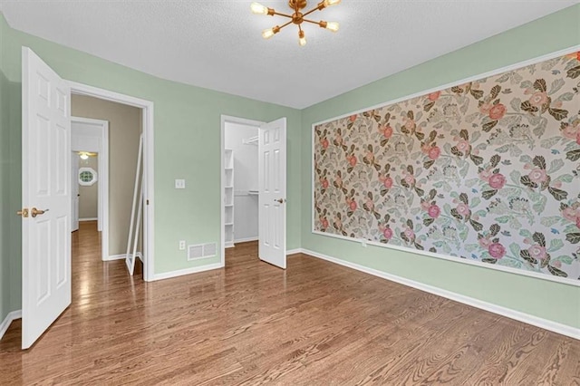 14440 W 187th Ter, Olathe, KS 66062 - unfurnished bedroom with wood finished floors, a chandelier, a textured ceiling, a spacious closet, and a closet