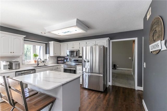 1503 Wrangler Way, Raymore, MO 64083 - kitchen with appliances with stainless steel finishes, white cabinets, a center island, a breakfast bar area, and dark wood-style floors