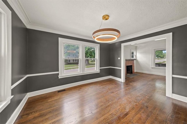 5900 Cherry St, Kansas City, MO 64110 - empty room with plenty of natural light, crown molding, wood finished floors, a fireplace with flush hearth, and a textured ceiling