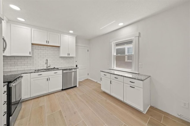 5900 Cherry St, Kansas City, MO 64110 - kitchen with appliances with stainless steel finishes, white cabinetry, light wood-style floors, light stone counters, and recessed lighting
