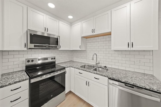 5900 Cherry St, Kansas City, MO 64110 - kitchen with appliances with stainless steel finishes, white cabinets, light stone counters, recessed lighting, and backsplash