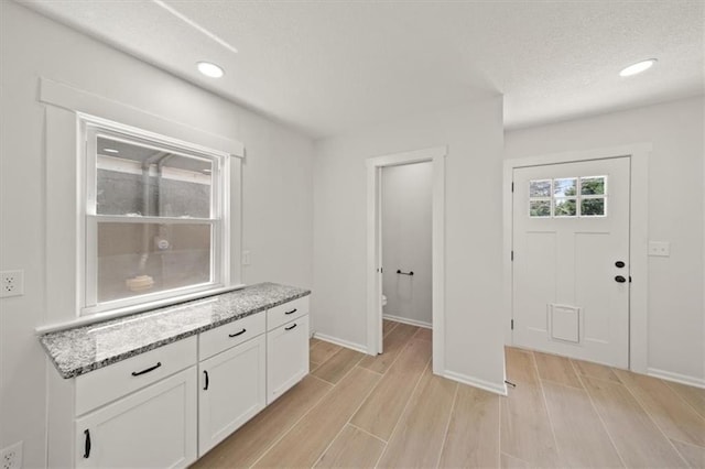 5900 Cherry St, Kansas City, MO 64110 - interior space featuring white cabinetry, light wood-type flooring, light stone countertops, a textured ceiling, and recessed lighting