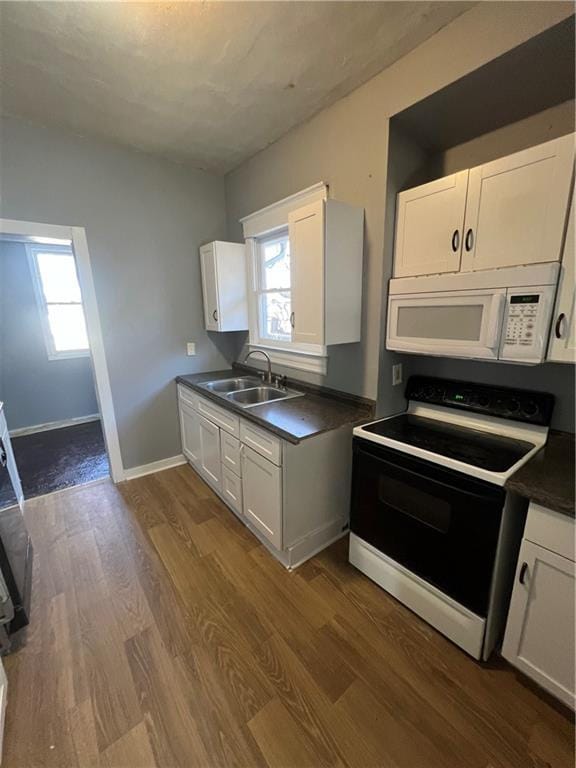 4902 E 17th St, Kansas City, MO 64127 - kitchen with white microwave, electric range oven, white cabinetry, and dark countertops