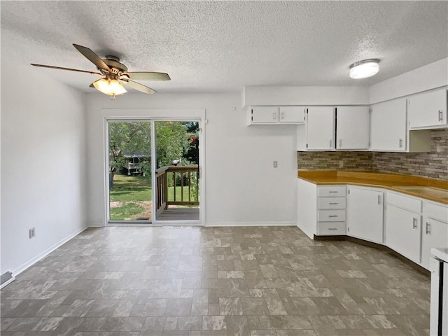 17604 E 19th Street Ct, Independence, MO 64057 - kitchen with ceiling fan, a textured ceiling, tasteful backsplash, white cabinets, and stone finish floors
