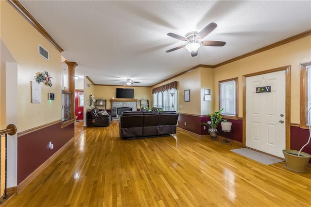 4000 SW Boulder Dr, Lees Summit, MO 64082 - living room featuring ceiling fan, light wood-style floors, crown molding, a fireplace, and decorative columns