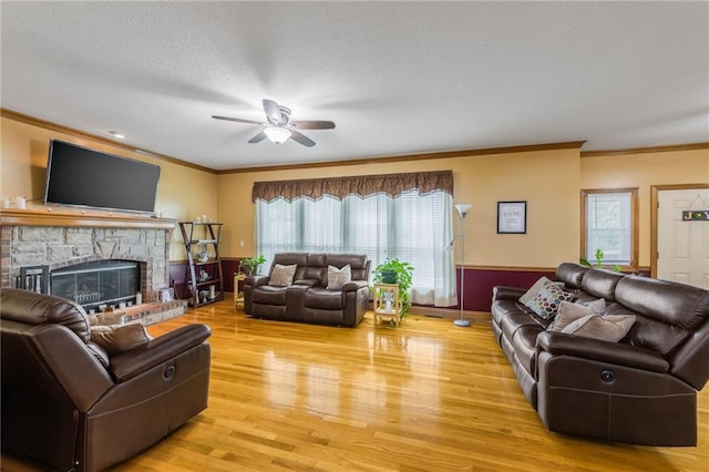 4000 SW Boulder Dr, Lees Summit, MO 64082 - living room featuring crown molding, light wood finished floors, ceiling fan, a stone fireplace, and a textured ceiling