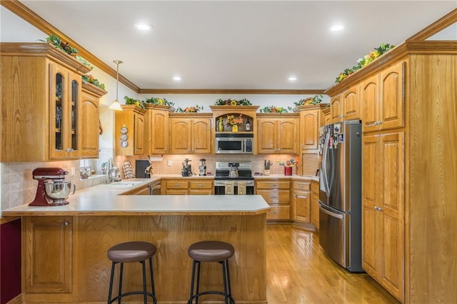 4000 SW Boulder Dr, Lees Summit, MO 64082 - kitchen featuring appliances with stainless steel finishes, a peninsula, light wood-style flooring, glass insert cabinets, and ornamental molding