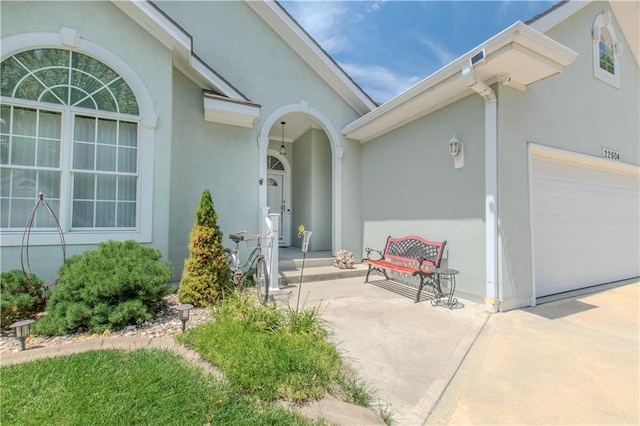 22604 Vincent St, Peculiar, MO 64078 - view of exterior entry with a garage, stucco siding, and driveway