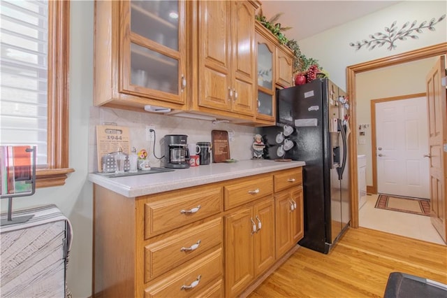 22604 Vincent St, Peculiar, MO 64078 - kitchen with black fridge with ice dispenser, light countertops, glass insert cabinets, brown cabinets, and light wood finished floors