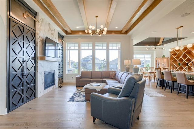 17325 Bradshaw St, Overland Park, KS 66221 - living room featuring a chandelier, beam ceiling, light wood finished floors, a fireplace, and a raised ceiling
