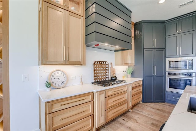 17325 Bradshaw St, Overland Park, KS 66221 - kitchen featuring stainless steel appliances, custom range hood, light wood finished floors, light countertops, and light brown cabinets