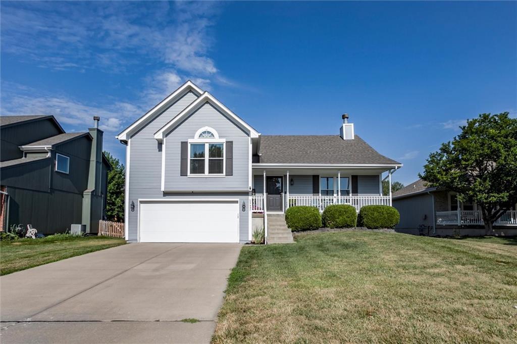 12497 S Marion St, Olathe, KS 66061 - tri-level home featuring a garage, a porch, concrete driveway, a front lawn, and a chimney