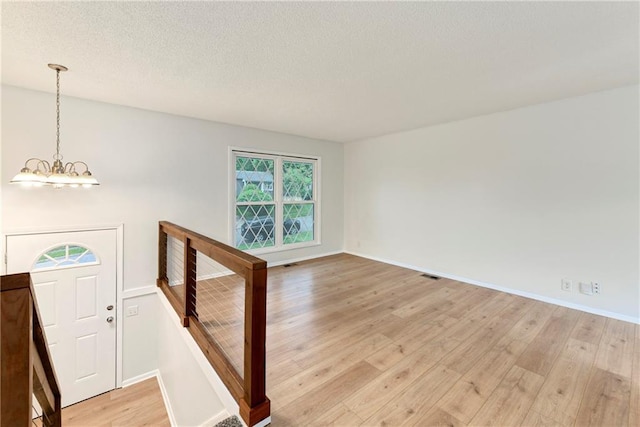 818 N Wigwam Trl, Independence, MO 64056 - empty room featuring light wood-style flooring, a chandelier, and a textured ceiling