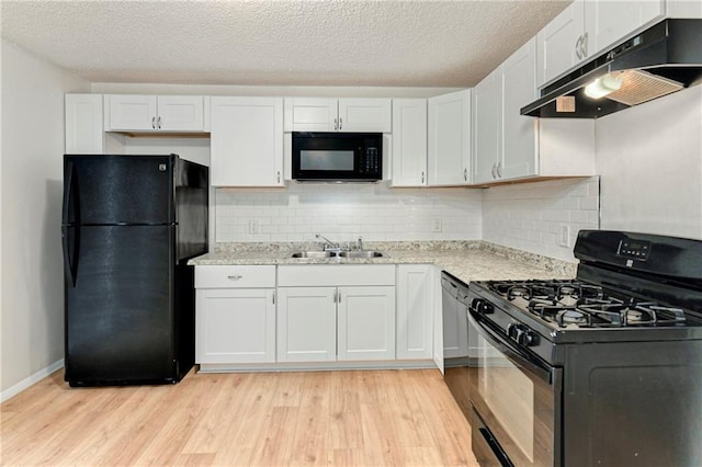 818 N Wigwam Trl, Independence, MO 64056 - kitchen with black appliances, under cabinet range hood, light wood-style flooring, white cabinets, and a textured ceiling