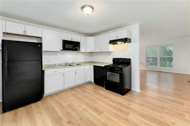 818 N Wigwam Trl, Independence, MO 64056 - kitchen with black appliances, under cabinet range hood, light wood-style floors, white cabinets, and a textured ceiling