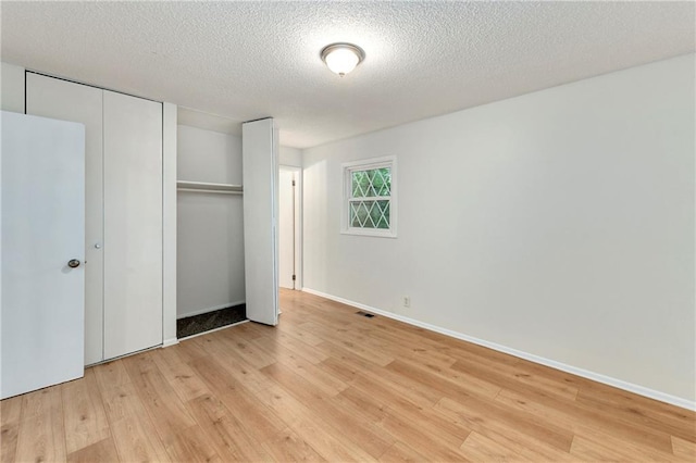 818 N Wigwam Trl, Independence, MO 64056 - unfurnished bedroom with light wood-type flooring, a textured ceiling, and a closet