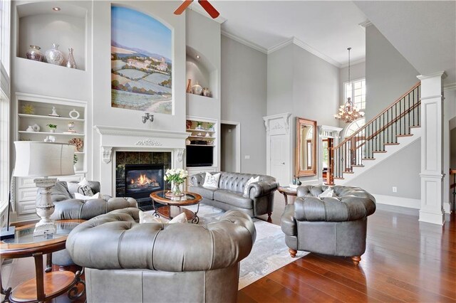 12333 Westgate St, Overland Park, KS 66213 - living room featuring dark wood-style flooring, built in shelves, a towering ceiling, a fireplace, and ornamental molding