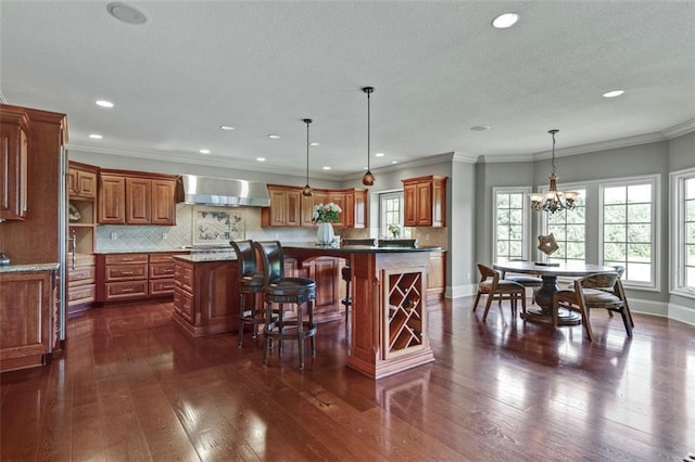 12333 Westgate St, Overland Park, KS 66213 - kitchen featuring wall chimney exhaust hood, a center island, brown cabinets, recessed lighting, and backsplash