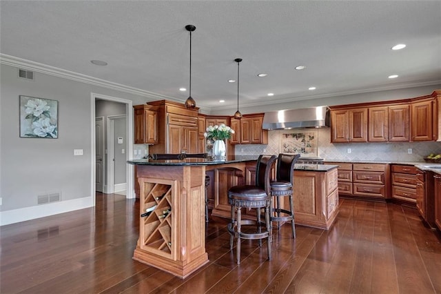 12333 Westgate St, Overland Park, KS 66213 - kitchen featuring wall chimney exhaust hood, brown cabinetry, dark wood-style floors, a center island, and decorative backsplash