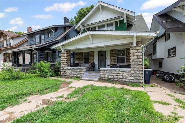 3443 Agnes Ave, Kansas City, MO 64128 - view of front of house featuring a porch, stone siding, and a front lawn