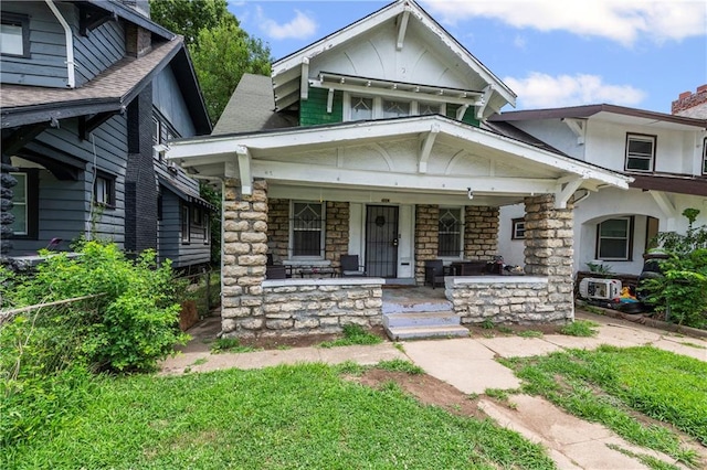 3443 Agnes Ave, Kansas City, MO 64128 - view of front facade featuring stone siding, a porch, a chimney, and a shingled roof