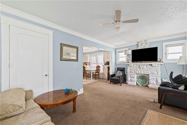 3443 Agnes Ave, Kansas City, MO 64128 - living room featuring ceiling fan, ornamental molding, a stone fireplace, a textured ceiling, and carpet floors