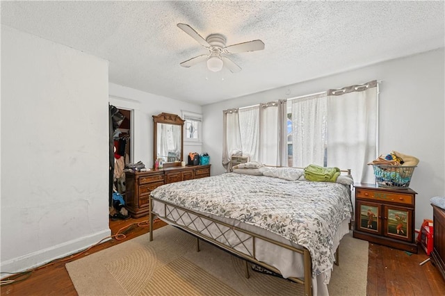 3443 Agnes Ave, Kansas City, MO 64128 - bedroom featuring wood finished floors, a textured ceiling, ceiling fan, and a spacious closet