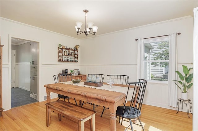 2010 Eugene Field Ave, Saint Joseph, MO 64505 - dining space with light wood-type flooring, a chandelier, ornamental molding, wainscoting, and a decorative wall