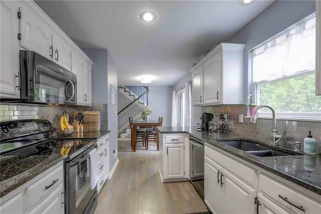 503 SW Creek Ridge Dr, Grain Valley, MO 64029 - kitchen with black appliances, white cabinetry, light wood finished floors, tasteful backsplash, and recessed lighting