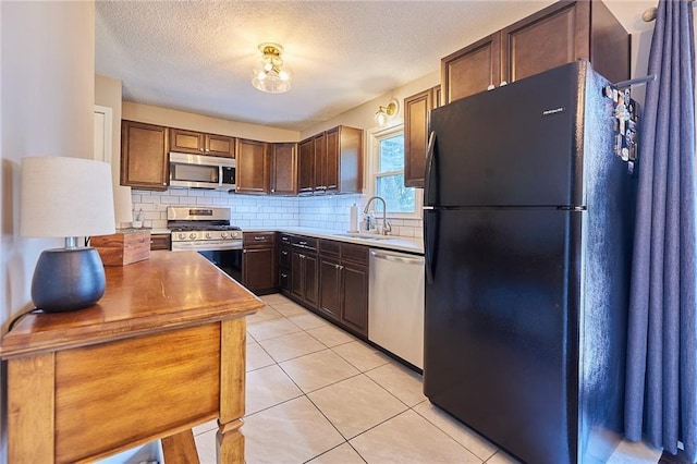 7725 Cleveland Ave, Kansas City, KS 66109 - kitchen with stainless steel appliances, backsplash, light tile patterned floors, a textured ceiling, and dark brown cabinetry