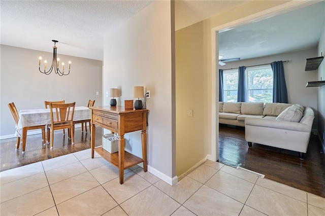 7725 Cleveland Ave, Kansas City, KS 66109 - dining area with a chandelier, light tile patterned flooring, ceiling fan, and a textured ceiling