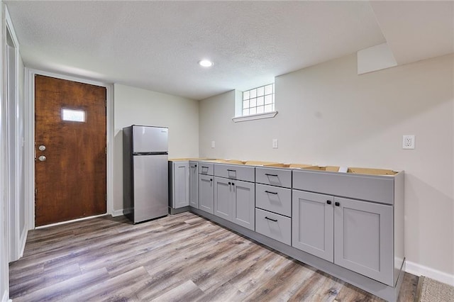 7725 Cleveland Ave, Kansas City, KS 66109 - kitchen featuring freestanding refrigerator, gray cabinets, light wood-style floors, a textured ceiling, and light countertops