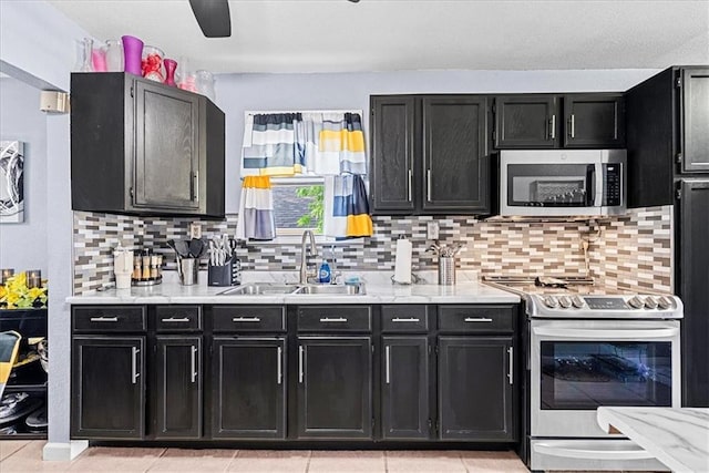 3021 Topping Ave, Kansas City, MO 64129 - kitchen with stainless steel appliances, dark cabinets, light countertops, and backsplash