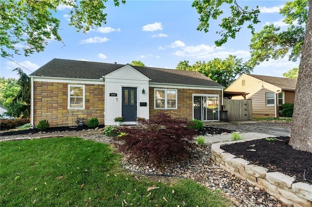 3600 NE 52nd Ter, Kansas City, MO 64119 - ranch-style house with stone siding, roof with shingles, and a front lawn
