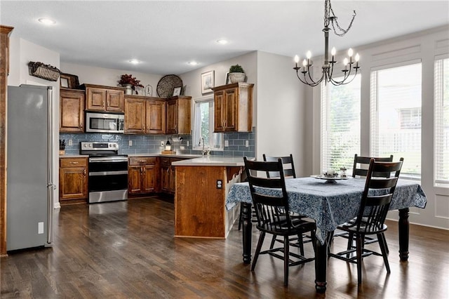 14920 S Roxburghe St, Olathe, KS 66061 - kitchen featuring appliances with stainless steel finishes, a peninsula, brown cabinetry, plenty of natural light, and recessed lighting