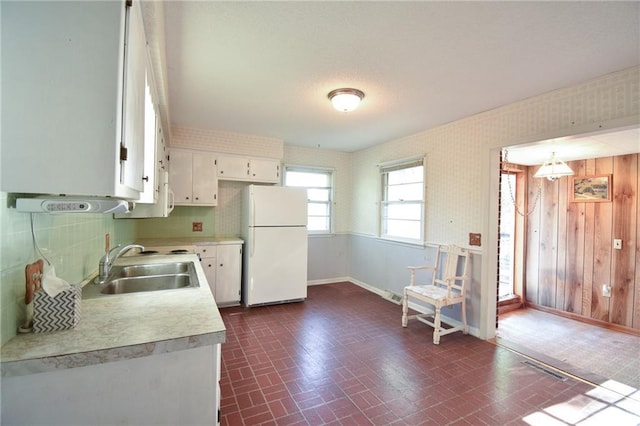 16210 Baxter Rd, Excelsior Springs, MO 64024 - kitchen with freestanding refrigerator, light countertops, white cabinetry, brick patterned floors, and wood walls