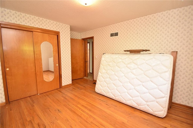 16210 Baxter Rd, Excelsior Springs, MO 64024 - bedroom with wood finished floors, a closet, wallpapered walls, and a textured ceiling
