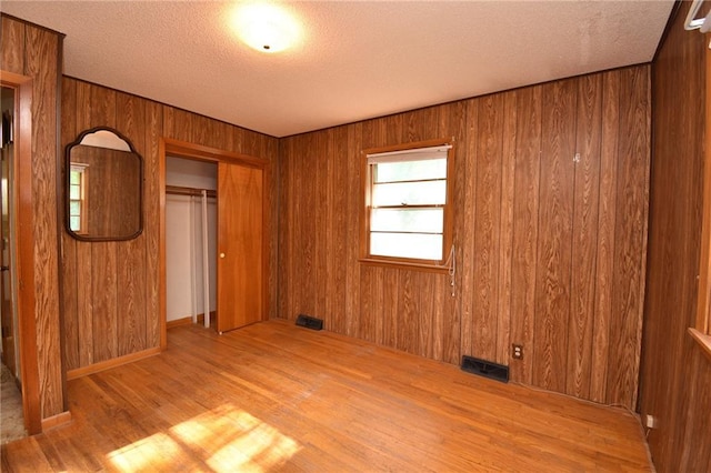 16210 Baxter Rd, Excelsior Springs, MO 64024 - unfurnished bedroom featuring wood finished floors, a textured ceiling, a closet, and wood walls