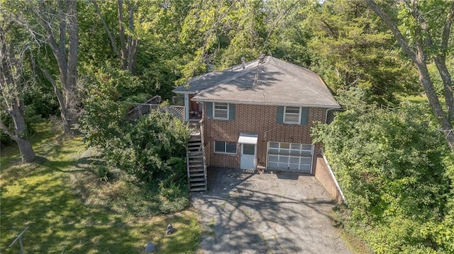 16210 Baxter Rd, Excelsior Springs, MO 64024 - view of front facade featuring brick siding, stairway, an attached garage, driveway, and a wooded view