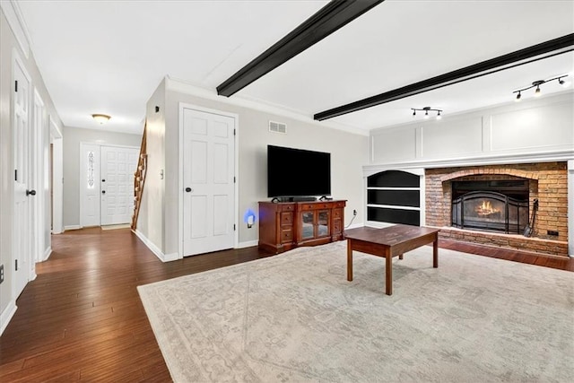 15820 W 150th Ter, Olathe, KS 66062 - unfurnished living room with dark wood-type flooring, a brick fireplace, rail lighting, and beamed ceiling
