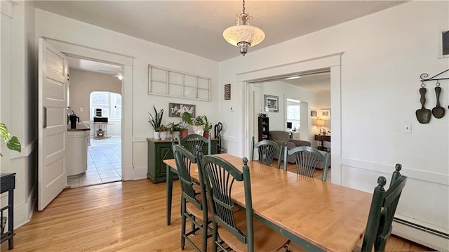 309 College St, Paola, KS 66071 - dining room featuring a baseboard radiator, healthy amount of natural light, and light wood-style floors