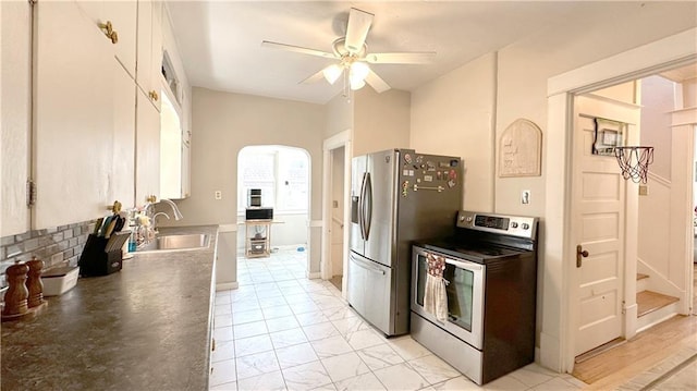 309 College St, Paola, KS 66071 - kitchen with appliances with stainless steel finishes, a ceiling fan, arched walkways, and dark countertops