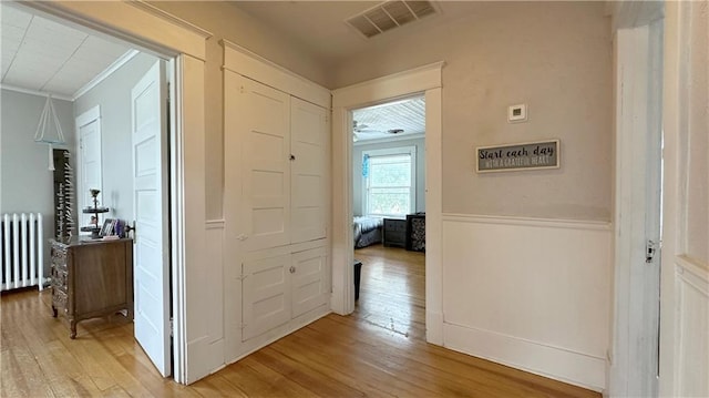 309 College St, Paola, KS 66071 - corridor with radiator heating unit, light wood finished floors, crown molding, and wainscoting
