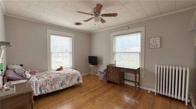 309 College St, Paola, KS 66071 - bedroom with radiator, ornamental molding, multiple windows, wood finished floors, and ceiling fan
