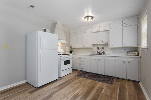 5921 Lexington Ave, Kansas City, MO 64123 - kitchen with white appliances, light countertops, light wood finished floors, white cabinetry, and tasteful backsplash