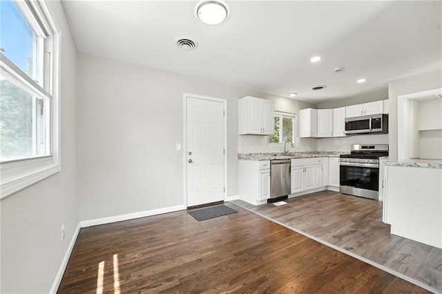 4916 N Manchester Ave, Kansas City, MO 64119 - kitchen featuring appliances with stainless steel finishes, white cabinets, dark wood-type flooring, light stone counters, and recessed lighting