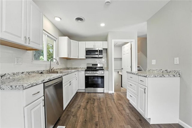4916 N Manchester Ave, Kansas City, MO 64119 - kitchen featuring appliances with stainless steel finishes, dark wood-type flooring, white cabinetry, and decorative backsplash